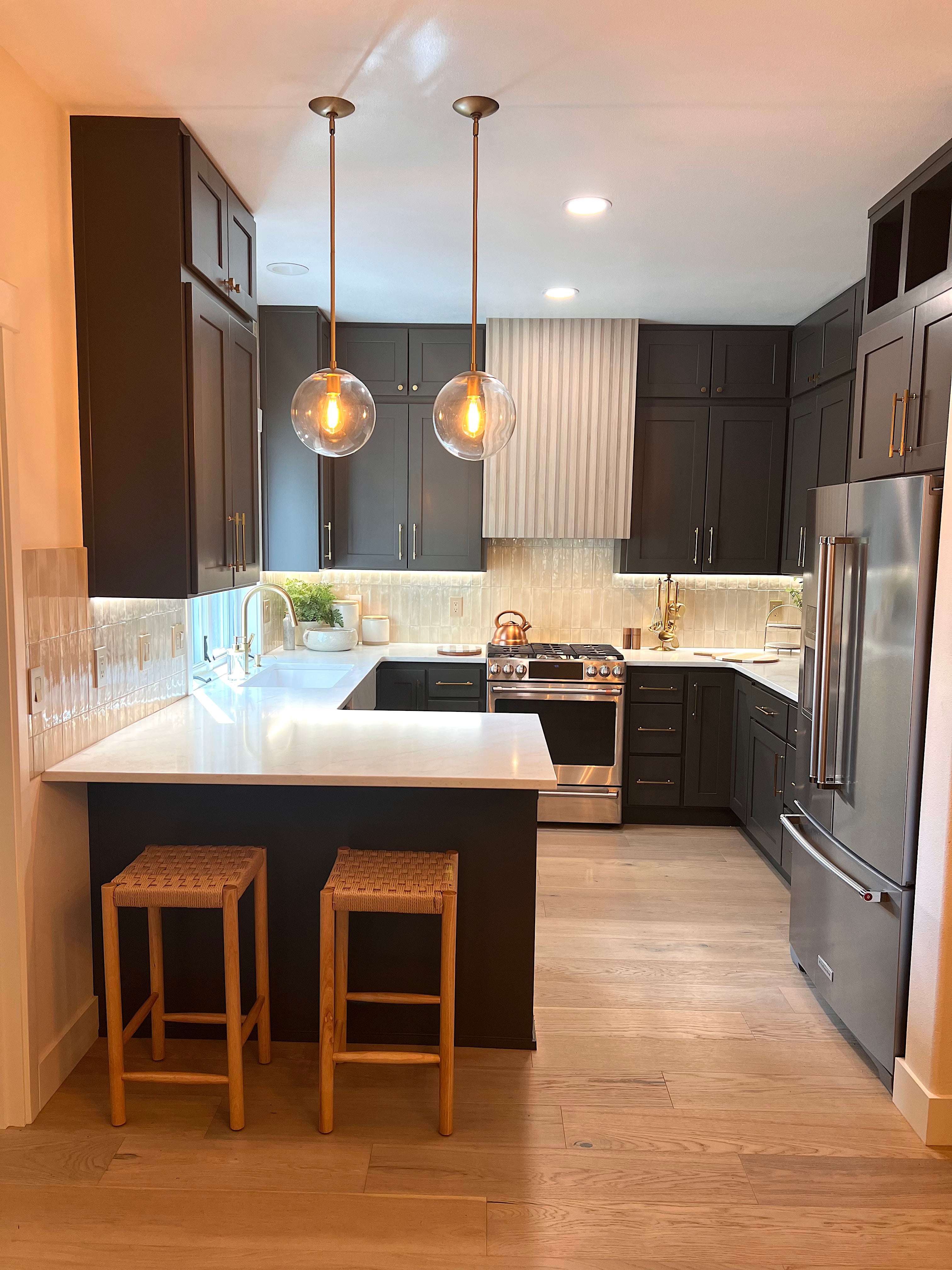 Modern kitchen with dark cabinets, stainless steel appliances, and wooden flooring.